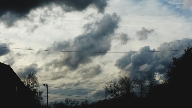 Niski kąt widoku pylonu elektrycznego na chmurnym niebie