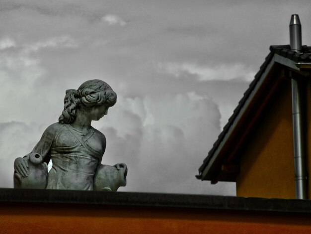 Niski kąt widoku rzeźby kobiety na tarasie na tle chmurnego nieba