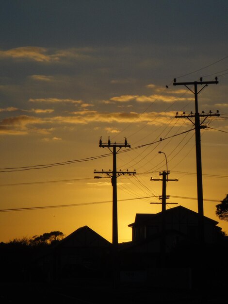 Zdjęcie niski kąt widoku siluety słupów elektrycznych na tle nieba podczas zachodu słońca