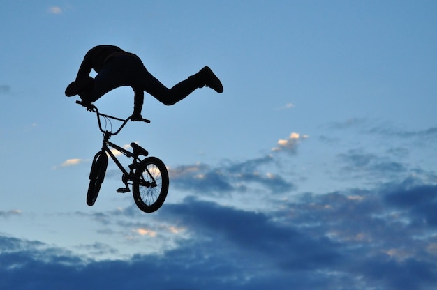Zdjęcie niski kąt widoku sylwetki mężczyzny z rowerem na tle nieba
