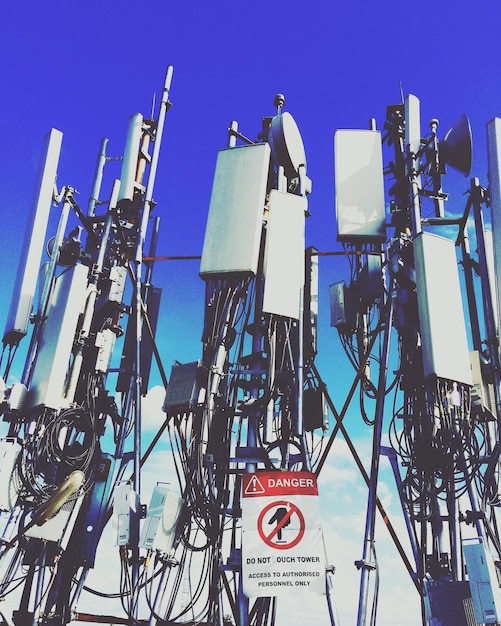 Zdjęcie niski kąt widoku wieży komunikacyjnej na tle jasnego niebieskiego nieba