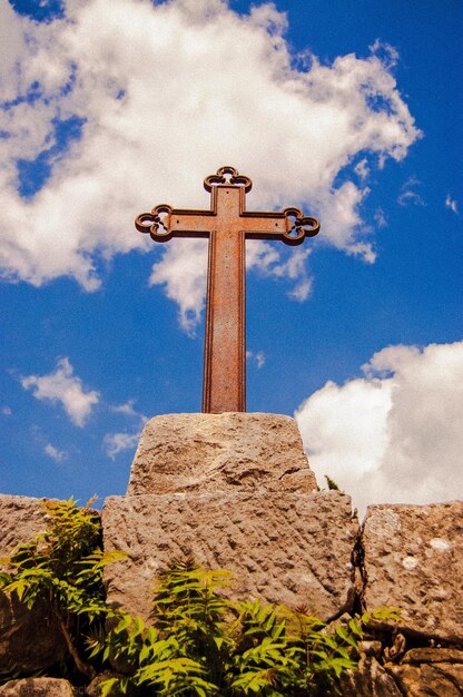 Zdjęcie niski kąt widoku zardzewiałego metalowego krzyża na skale na tle nieba
