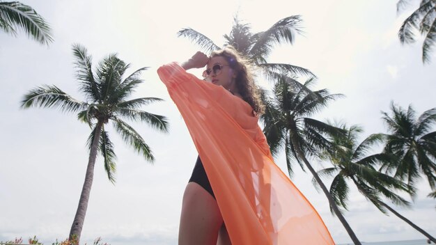 Zdjęcie niski kąt widzenia pięknej kobiety w odzieży plażowej stojącej na zewnątrz