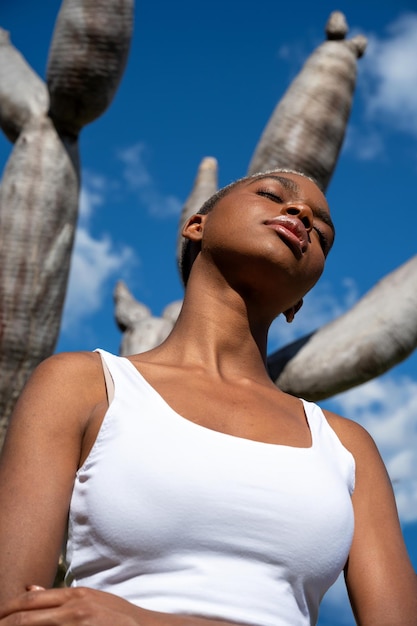 Niski kąt zrelaksowanej Afroamerykanki stojącej z zamkniętymi oczami na tle smoczego drzewa i ciesz się