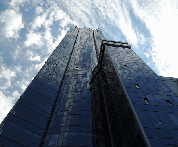 Niski punkt widoku wielopiętrowego budynku ze szklaną fasadą i chmurami na niebie