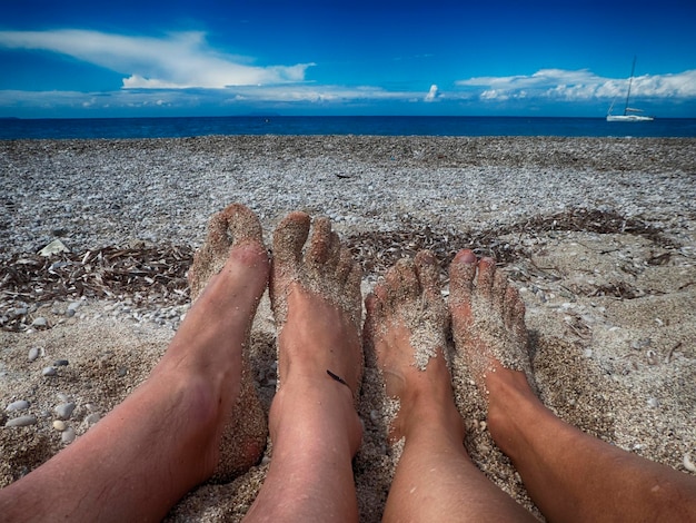 Zdjęcie niższa część ludzi relaksujących się na plaży na tle nieba