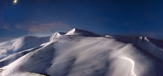 Noc pokryty śniegiem grzbiet górski w księżycu i promienie pierwszego brzasku pastelowe oświetlenie, Ukraina, Karpaty, Pasmo Svydovets, Góra Blyznytsja.