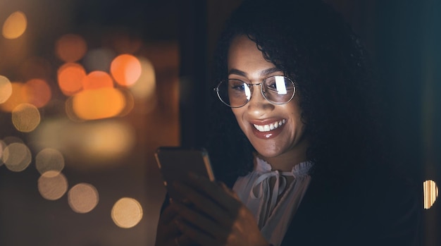 Nocna czarna kobieta i telefon biznesowy ze światłami bokeh do połączenia z siecią komunikacyjną Szczęśliwy przedsiębiorca w ciemności do sieci społecznościowych lub aplikacji mobilnej ux do makiety inwestycyjnej