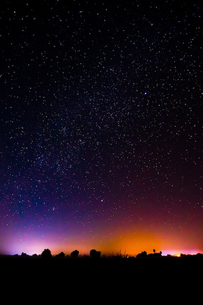 Nocna sceneria z kolorową i jasnożółtą Drogą Mleczną Pełną gwiazd na niebie.