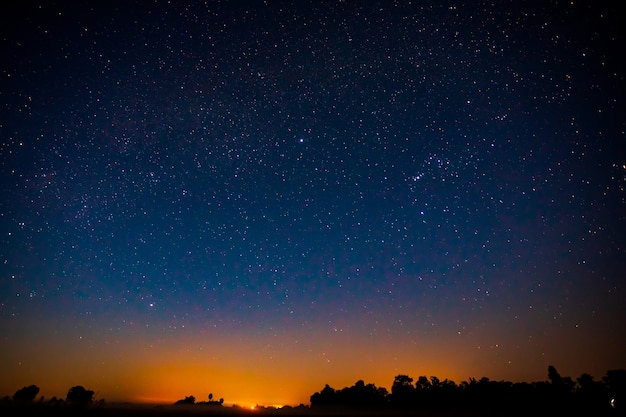 Nocna sceneria z kolorową i jasnożółtą Drogą Mleczną Pełną gwiazd na niebie.