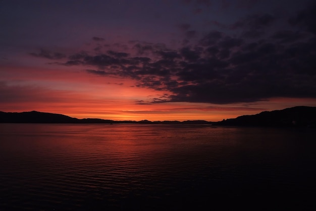 Nocny pejzaż morski w Bergen, Norwegia. Woda morska lub oceaniczna pod ciemnym niebem magenta na naturalnym tle. Natura, ekologia, wanderlust, koncepcja wakacji