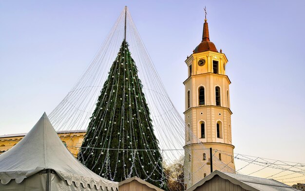 Nocny pejzaż z Jarmark Bożonarodzeniowy na Placu Katedralnym w zimie Wilno, Litwa. Dekoracje na jarmark adwentowy i stragany z artykułami rzemieślniczymi na bazarze. Litewska ulica Boże Narodzenie i święta