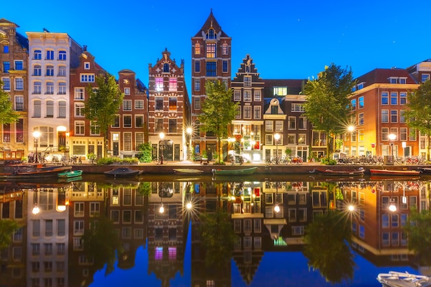 Nocny widok na kanał Amsterdam Herengracht z typowymi domami holenderskimi i ich odbicia, Holandia, Holandia.