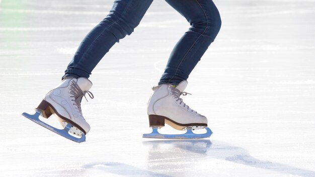 Nogi kobiety w dżinsach i białych łyżwach na lodowisku. hobby i wypoczynek. Sporty zimowe