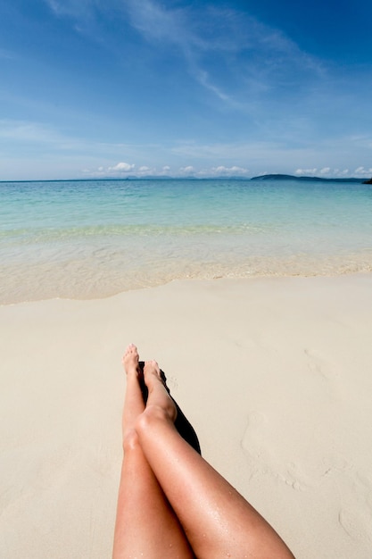 Nogi Młodej Kobiety Leżącej W Piasku Na Plaży Na Tle Oceanu I Nieba