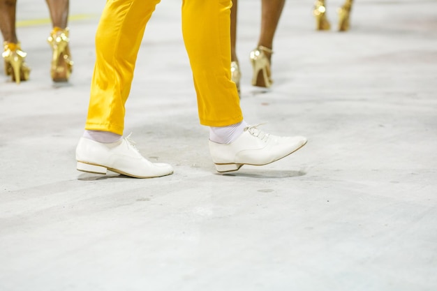 Nogi sambisty tańczącego w żółtych spodniach i białych butach na sambodromo da marques de sapucai w Rio de Janeiro