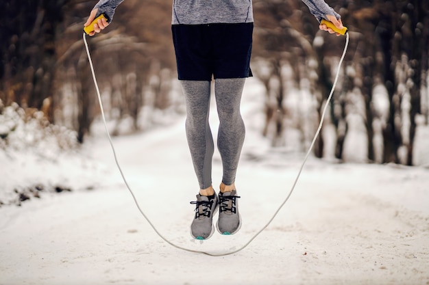 Nogi, skakanie po linie na zaśnieżonej ścieżce w zimie. Sporty zimowe, ćwiczenia cardio, zdrowe nawyki