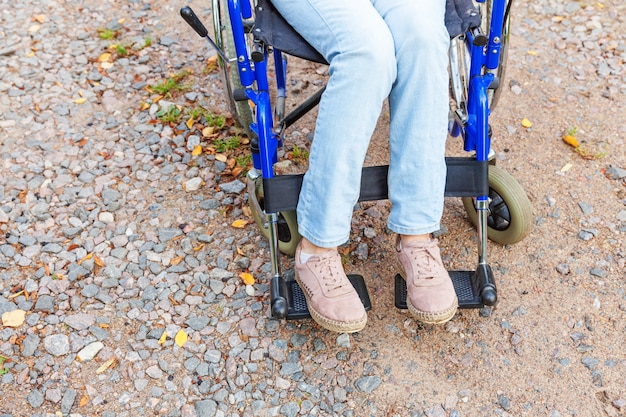 Zdjęcie nogi stopy upośledzenia kobieta w wózku inwalidzkim na drodze w parku szpitalnym, czekając na usługi dla pacjentów. nie do poznania sparaliżowana dziewczyna w nieważnym krześle dla osób niepełnosprawnych na zewnątrz. koncepcja rehabilitacji.
