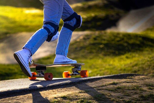 Nogi W Niebieskich Dżinsach I Nakolanniki Jeżdżą Na Deskorolce W Skateparku