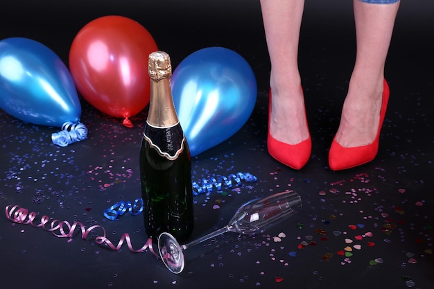 Nogi z szampanem konfetti i balonami na podłodze