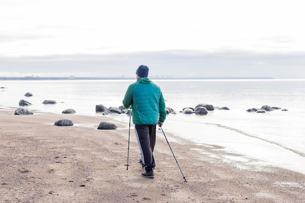 Nordic walking widok z tyłu na starszych starszych mężczyzn rasy kaukaskiej w Europie spacery z laskami w pobliżu jeziora Ćwiczenia sportowe dla zdrowego kręgosłupa i terapii stawów dla zdrowia widok z tyłu