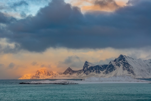 Norwegia zimą. Opuszczone górzyste wybrzeże oceanu. Gęste chmury i słońce