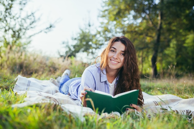 Nostalgiczna nastolatka siedzi w parku i czyta książkę