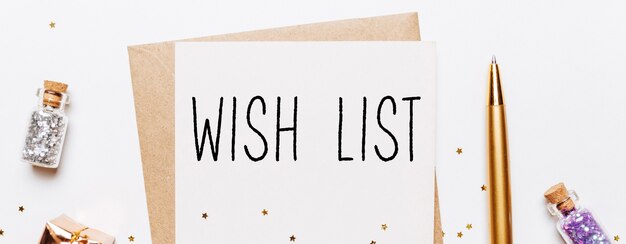 Zdjęcie notatka z listy życzeń z kopertą, prezentami i złotymi gwiazdami brokatu na białej powierzchni. wesołych świąt i nowego roku koncepcja