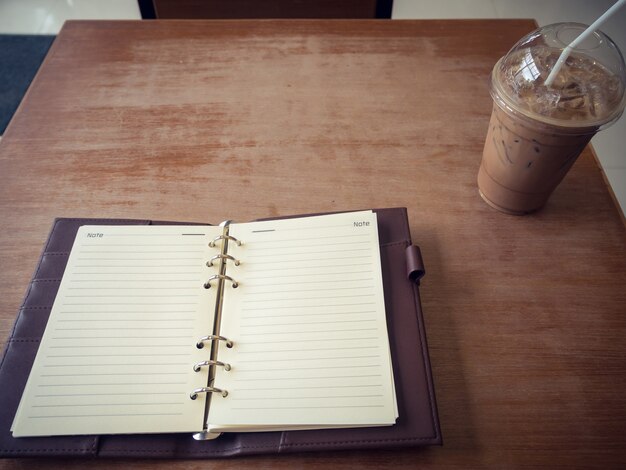 Zdjęcie notatnik i lodowa kawa na drewnianym tle