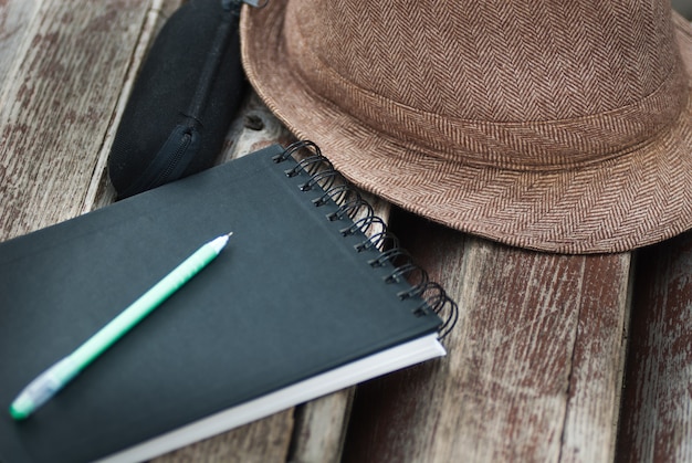 Zdjęcie notatnik, patelnia, etui na okulary i kapelusz na ławce w parku z bliska