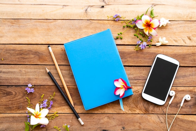 Notatnik, telefon komórkowy i kwiaty na drewnianym stole