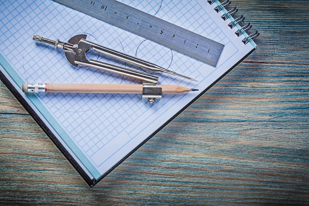 Notatnik w kratkę metalowa linijka rysująca ołówek kompasowy na zabytkowej drewnianej desce