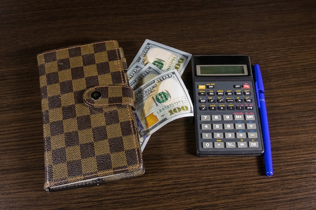 Notatnik z dolarami, długopisem i kalkulatorem na biurku. Koncepcja finansowa
