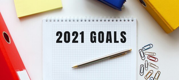 Notatnik z napisem GOALS 2021 na białej powierzchni, w pobliżu teczki z dokumentami