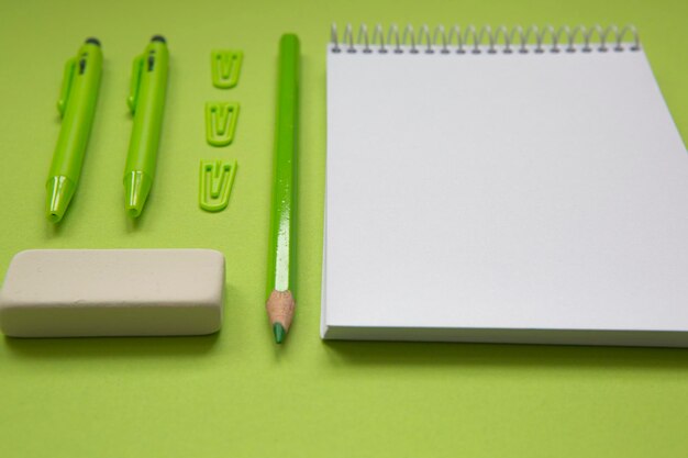 Notatnik z pustą kartką na pistacjowo zielonym tle, razem z ołówkiem i różnymi st