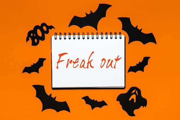 Notatnik z tekstem halloween Freak out on white and orange background