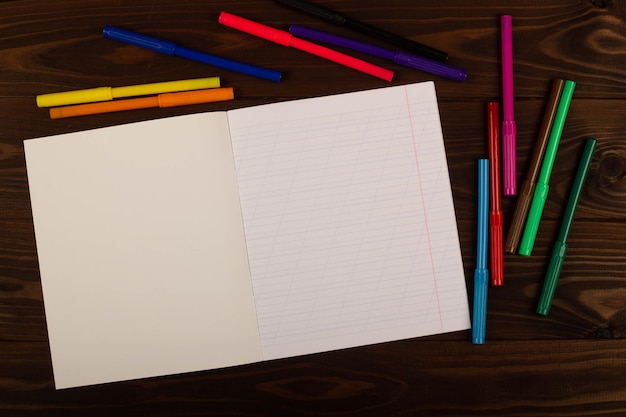 Notebook szkolny z ukośnymi liniami kolorowy flamaster na drewnianym tle stołu Pusty arkusz