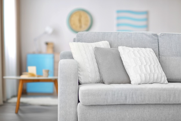 Nowa przytulna kanapa z poduszkami w nowoczesnym wnętrzu pokoju