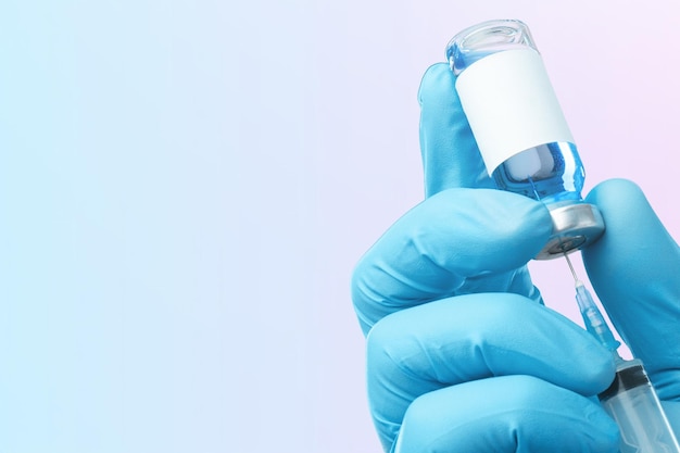 Nowa szczepionka koronawirusowa w rękach lekarzy lub pielęgniarek w niebieskich gumowych rękawiczkach.