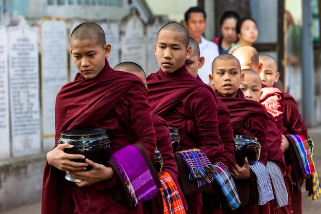 Nowicjusze buddyjscy czekają na jałmużnę na ulicy Amarapura. Myanmar