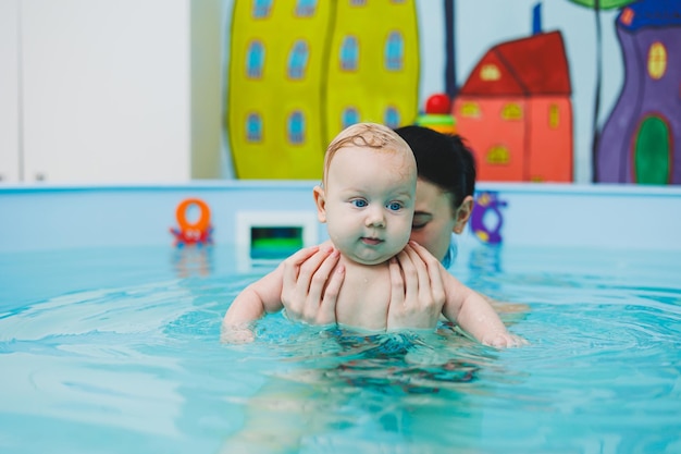 Nowo narodzone dziecko pływa w basenie Nauczanie dzieci pływać Dziecko uczy się pływać w basenie z trenerem Dziecko naucza się pływać Rozwój dziecka