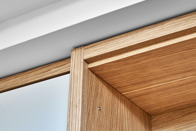 Nowoczesna drewniana szafa z płaskim palcem i jasnoszarym widokiem na zbliżenie drzwi szafy