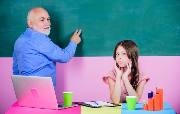 Nowoczesna edukacja Zmęczony uczeń Starszy nauczyciel i lekcja w szkole dla dziewcząt Nowoczesna wiedza Nowoczesna metoda nauczania Ucz się ciężko Uczeń i nauczyciel przy tablicy Laptop uczennica i nauczyciel