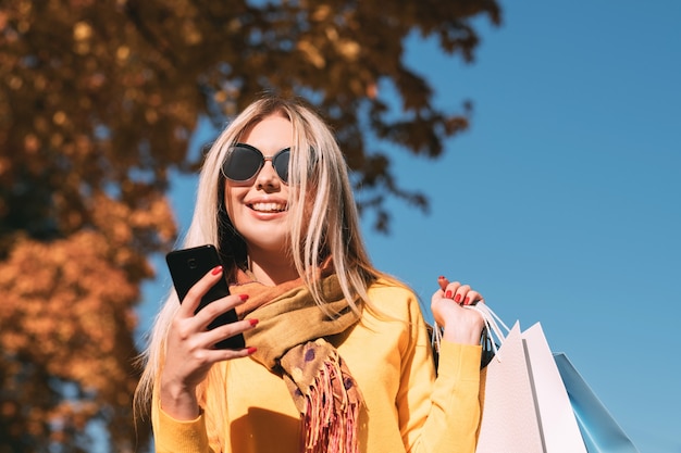 Nowoczesna kobieta czas wolny Szczęśliwa pani spaceru z torby na zakupy, rozmawiając przy użyciu smartfona