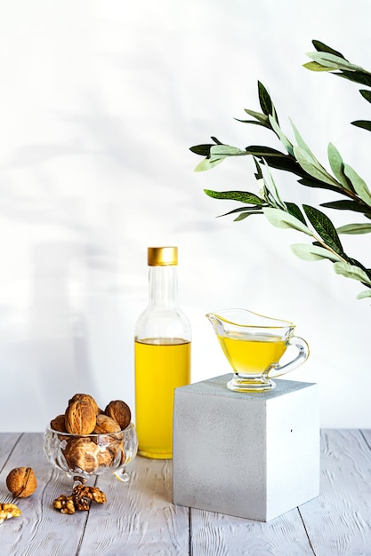 Nowoczesna martwa natura z butelką oleju i szklaną miską z gałązką oliwną orzechów włoskich