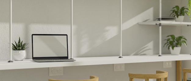 Nowoczesna minimalistyczna biała przestrzeń coworkingowa z makietą laptopa i roślinami dekoracyjnymi