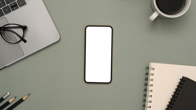Nowoczesne biurko tło z makietą białego ekranu smartfona na szarym tle widok z góry