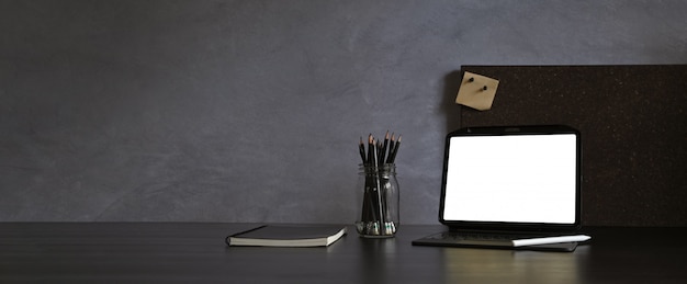 Zdjęcie nowoczesne ciemne miejsce do pracy z tabletem i rysikiem na czarnym stole i ścianie na poddaszu