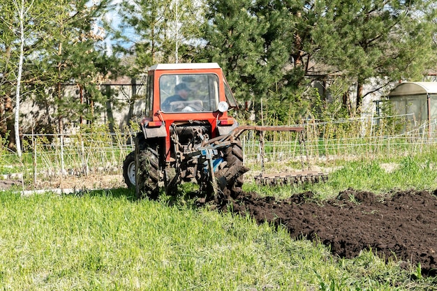 Nowoczesne maszyny do traktorów czerwonych orka łąka rolnicza w gospodarstwie na wiosnę jesień Rolnik uprawiający i uprawiający glebę przed siewem roślin i upraw natura wieś scena wiejska