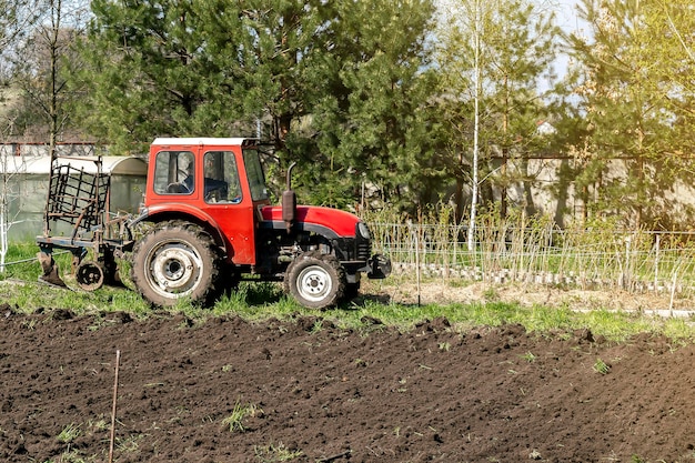 Nowoczesne maszyny do traktorów czerwonych orka łąka rolnicza w gospodarstwie na wiosnę jesień Rolnik uprawiający i uprawiający glebę przed siewem roślin i upraw natura wieś scena wiejska